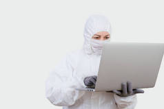 女医生穿着防护服，通过互联网戴口罩。带有白色背景笔记本的辅助医务人员.