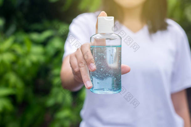 女用手将清洁剂凝胶放在抽水机中，用于室外手部卫生巾保护