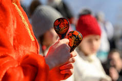 木制勺子，手上拿着俄罗斯的传统装饰品，手里拿着一个穿着红色民族服装的女孩。嘉年华民间乐器。用木制勺子玩