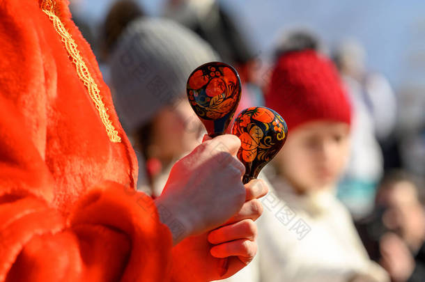 木制<strong>勺子</strong>，手上拿着俄罗斯的传统装饰品，手里拿着<strong>一个</strong>穿着红色民族服装的女孩。嘉年华民间乐器。用木制<strong>勺子</strong>玩