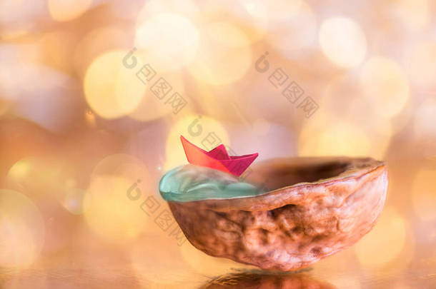 红色纸船在核桃壳上闪烁着金光背景的概念梦想，夏天，大海
