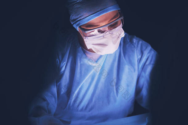在黑暗背景下做手术的医生.