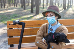 一个戴着面具和手套的时髦女人，让她远离了考拉威斯。在城市和公园里使用电动车是为了安全。和她的狗玩的开心.