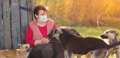 戴着医疗面罩的女志愿者和无家可归的狗站在户外。志愿服务和动物收容所的概念。当你有狗的时候会更孤独