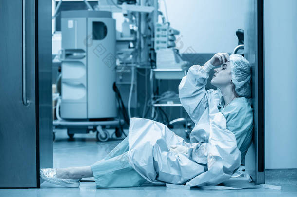 医疗外科的概念，科维德19号。精疲力竭的医生在重症监护病房里<strong>劳累</strong>过度大流行病，孤独，医生的努力工作，呆在家里。蓝色单色