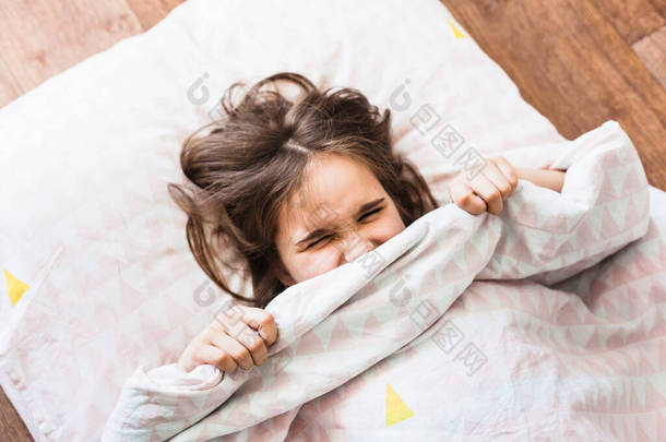 小女孩睡在枕头上，用毛毯、钢笔、婴儿睡眠、放松、欢乐、早晨、柔软的玩具、家庭和家做掩护，女孩不想起床去上学