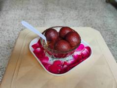 Gulabjamun在盘子里甜食在盘子里.背景模糊的红色长臂猿.