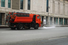 装有水桶的橙色卡车在路上浇水