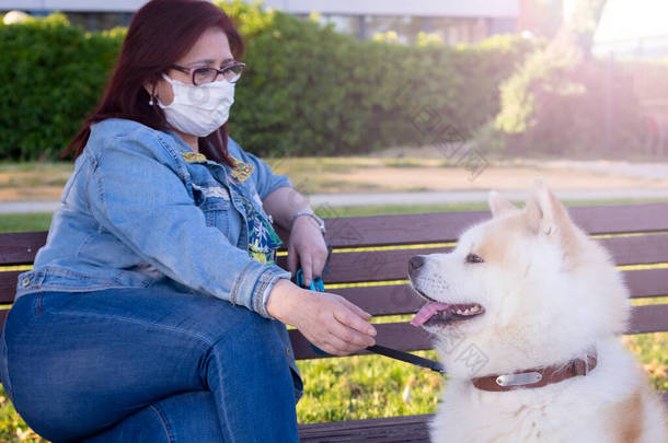 一名妇女带着她的狗和医疗面具坐在公园的面包车里，<strong>受到</strong>检疫