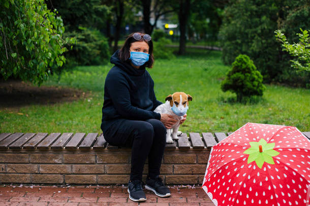 戴着防护外科口罩的女人和戴着口罩的杰克 · 罗斯塞尔犬坐在一起。中<strong>国</strong>的<strong>考</strong>氏病COVID-19对宠物有危险