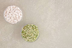 有机干裂开的浅绿色豌豆和放在玻璃碗里的白色Haricot豆。淡淡的背景上的豆科植物。素食者的健康食品。横向的位置。顶部视图。复制空间