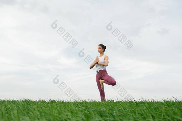 一个苗条<strong>身材</strong>的小女孩在绿地里做<strong>瑜伽</strong>