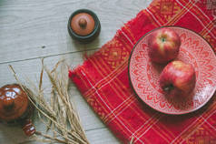 鲜红色的Plakhta，红色的民族盘，传统的装饰品，麦穗，苹果和粘土锅，木制背景