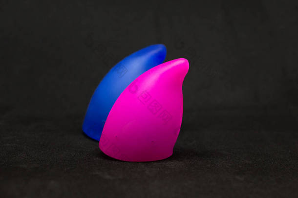 两个色彩艳丽的月经杯，蓝色和粉色，尖端光滑，大<strong>小</strong>和容量不同- 20毫<strong>升</strong>和30毫<strong>升</strong>在孤立的黑色背景，生态可重复使用，零浪费工具