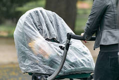 春天里的一个雨天，一位母亲和她的孩子坐在用胶卷包裹的婴儿车里散步.