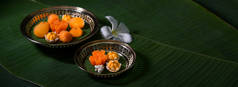 在黄铜盘上享用的几种泰国传统甜点的近景，这些甜点有复制空间和装饰在香蕉叶上的花朵