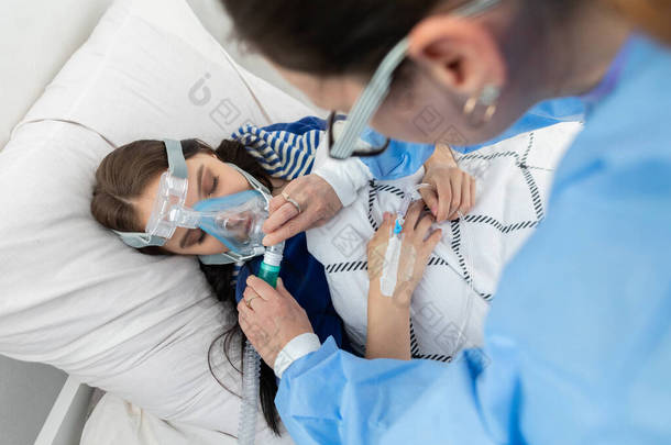 医生控制通风机的连接.这个少年躺在医院的床上。呼吸道氧气面罩.