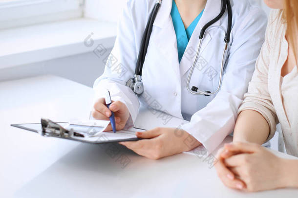 医生和病人坐在医院的办公桌前讨论一些事情，特写。医药和保健