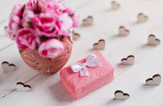 带有红心、礼品盒和粉红玫瑰花束的古色古香背景，装在白色木板上。假日和爱情的概念