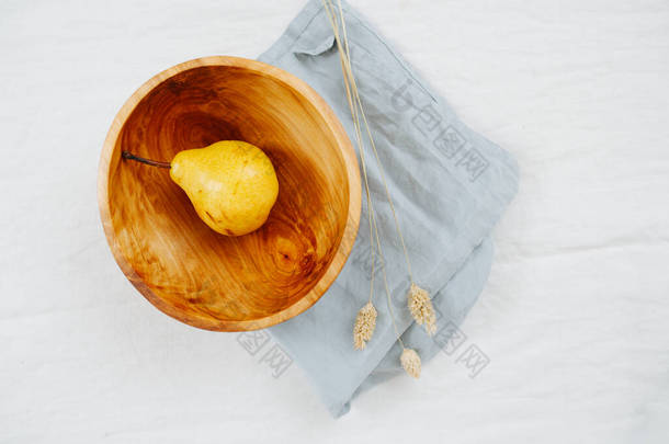 成熟的梨子放在木碗里，站在白纸上。顶部视图.