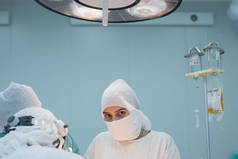 行动小组。女外科医生在手术过程中看着摄像机。无菌手术室的条件。对病人内脏器官的外科干预