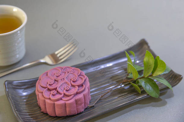一种非传统的中国月饼，用紫色的日本山药和一杯绿色的黑色陶<strong>瓷盘</strong>做成。顶部视图，灰色计数器顶部背景.