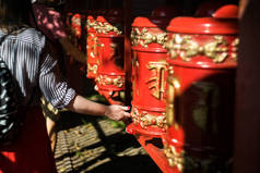 女孩在佛教寺庙里扭动着祈祷鼓。红色的khurde在阳光下。Mani鼓