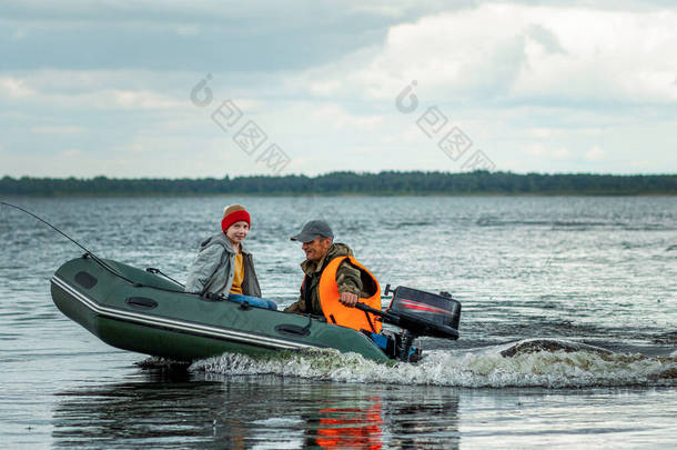 爷爷和孙子在湖上坐汽艇.家庭的概念，暑假，<strong>世代</strong>。复制空间