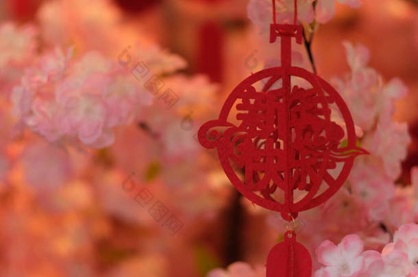 把中文里的新年快乐这个词当作挂在树上的装饰品。模糊的粉红花朵<strong>背景</strong>.中国<strong>春节</strong>的概念