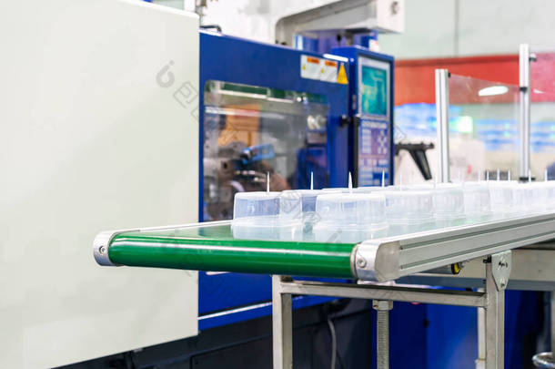 工厂<strong>自动化</strong>输送带注塑机生产过程中生产的多排透明塑料杯或塑料盒