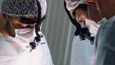 执行手术的医疗队。行动。在手术过程中，在手术室内戴双目百叶窗的外科医生的近视.