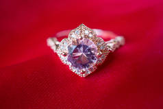 红色面料背景上镶嵌蓝宝石宝石的珠宝豪华粉色金戒指