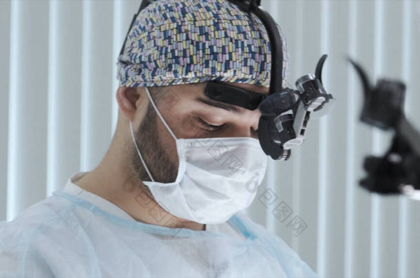 戴口罩和外科眼镜的外科医生做手术。行动。专业外科医生在手术过程中的面部特写。配备最新医疗技术的外科医生