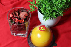 中文：幸福，粘在橙子蛋糕上，干花插在茶杯里，绿叶插在红色的地板上。农历新年概念.