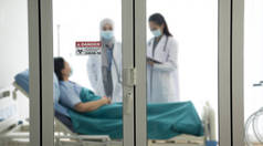 亚洲女医生穿着防护服在医院病房检查和治疗病人，有选择地注重门贴