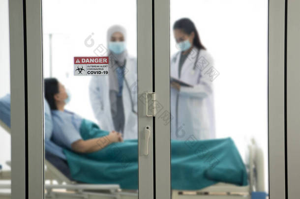 亚洲女医生穿着防护服在医院病房检查和治疗病人，有选择地注重<strong>门贴</strong>