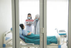 亚洲女医生穿着防护服在医院病房检查和治疗病人，有选择地注重门贴