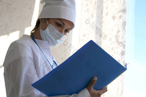 戴口罩站着的女医生带着文件夹看病史