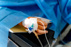 注射器一种导管，病人手里拿着注射器躺在手术台上全麻下的外科手术过程。麻醉是通过注射器进行的.