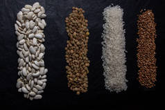 在黑色背景上，平铺着不同类型的谷物和谷类的构图。谷物、谷物和豆类的分配