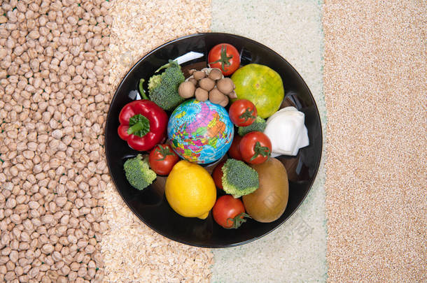 世界粮食日的概念。新鲜蔬菜、黑盘水果、燕麦和绿色背景的米。顶部视图
