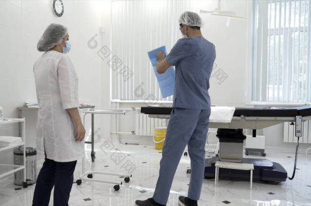 男<strong>护士</strong>和女<strong>护士</strong>为手术准备一个无菌室。行动。手术前病房护理人员的后视镜.