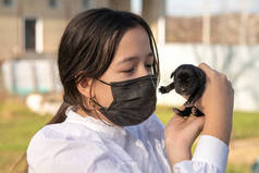 一个戴着防护面具的女孩抱着一只新生的拉布拉多犬。爱。温柔的概念。第一天的生活.