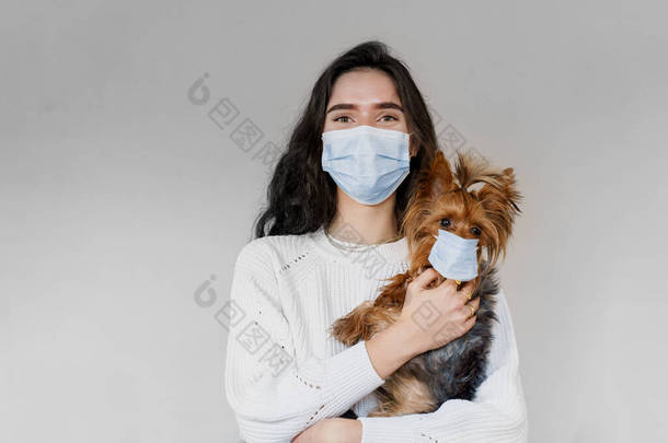 带着戴着口罩的狗的兽医。有吸引力的兽医持有约克郡犬。大流行病。验尸官的概念。流感爆发期间的健康保障