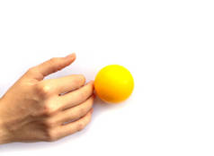 一只雌手在白色背景上摸黄色塑料球的指尖