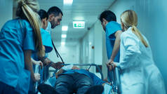急诊部：医生、护士和外科医生通过医院走廊运送严重受伤病人躺在担架上。医护人员迅速将病人送进手术室.