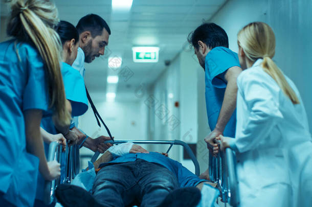 急诊部：医生、<strong>护士</strong>和外科医生通过医院走廊运送严重受伤病人躺在担架上。<strong>医护人员</strong>迅速将病人送进手术室.