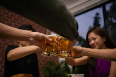 一群亚洲工人在聚会上欢呼雀跃喝啤酒.他们下班后在餐馆或夜总会休息.