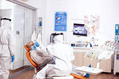 牙科医生护士穿着危险物品服给病人量体温