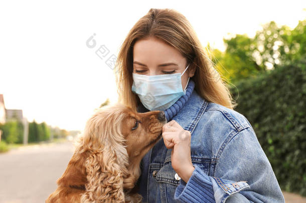 戴着防护面罩的女人在户外带着英国<strong>可卡</strong>犬。COVID-19大流行病期间的走狗